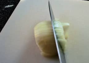 Knife slicing through onion